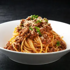 Pyszne spaghetti z bogatym sosem bolognese, posypane parmezanem i natką pietruszki. Idealne danie z makaronem z mięsem mielonym.