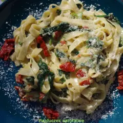 Pyszny makaron ze szpinakiem i suszonymi pomidorami, posypany parmezanem. Idealny na szybki obiad.