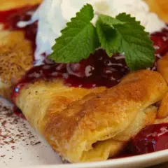 Pyszny omlet Ani gotuje się z wiśniami i bitą śmietaną, posypany kakao.