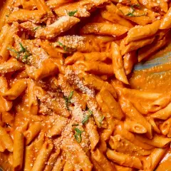 Penne alla vodka w kremowym, pomarańczowym sosie, posypane parmezanem i bazylią.