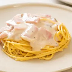 Pyszny makaron z jajkiem i boczkiem w kremowym sosie, podany na talerzu.