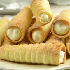 Stos rurki z kremem, posypane cukrem, kuszą słodkim nadzieniem. Idealne na deser!