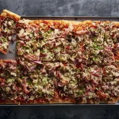 Domowa pizza na blachę z szynką, pieczarkami i oliwkami. Idealny przepis na szybki obiad.
