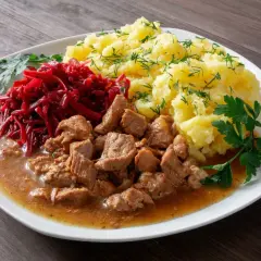 Gulasz z łopatki z ziemniakami i buraczkami, udekorowany natką pietruszki i koperkiem. Pyszny, domowy obiad.