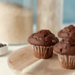 Pyszne muffinki z czekoladą, gotowe do zjedzenia. W tle słoiki z cukrem i mąką.