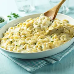Pyszne mac and cheese przepis w białej misce, z drewnianą łyżką nabierającą porcję kremowego makaronu z serem.