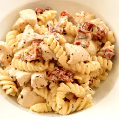 Pyszny makaron fusilli z kawałkami kurczaka i aromatycznymi suszonymi pomidorami w kremowym sosie.