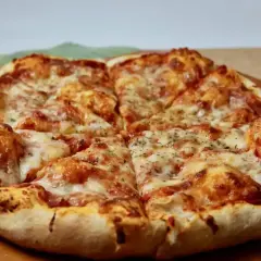 Pyszne, gorące ciasto na pizzę z ciągnącym się serem i aromatycznymi ziołami, pokrojone na kawałki.