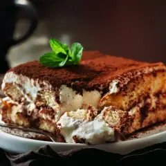 Pyszne tiramisu Ani gotuje, z kremem i biszkoptami, posypane kakao i udekorowane miętą.
