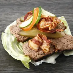Pyszny pasztet mieszany drobiowo-wieprzowy na liściu sałaty, z chrupiącym boczkiem, ogórkiem i pomidorem.