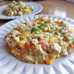Pyszne risotto z kurczakiem, papryką i bazylią, podane na białym talerzu. Idealne na obiad.