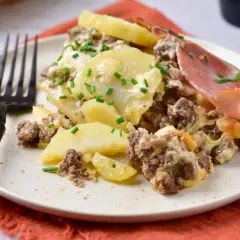 Zapiekanka ziemniaczana z mięsem mielonym, jak u Ani Gotuje, na talerzu, posypana szczypiorkiem. Pyszne danie!