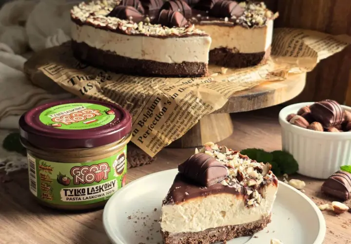 Pyszne ciasto Kinder Bueno z mascarpone, udekorowane orzechami i czekoladkami. Obok słoik pasty z orzechów laskowych.