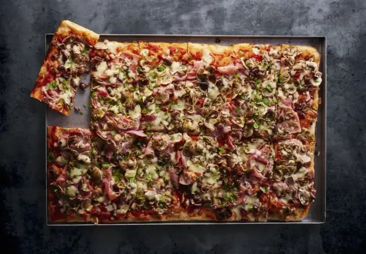 Domowa pizza na blachę z szynką, pieczarkami i oliwkami. Idealny przepis na szybki obiad.