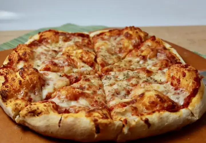 Pyszne, gorące ciasto na pizzę z ciągnącym się serem i aromatycznymi ziołami, pokrojone na kawałki.