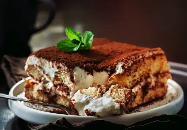 Pyszne tiramisu Ani gotuje, z kremem i biszkoptami, posypane kakao i udekorowane miętą.