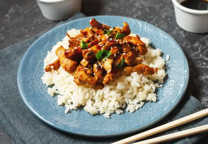 Pyszny kurczak w sosie teriyaki, podany na białym ryżu, posypany sezamem i szczypiorkiem. Idealny posiłek na szybki obiad.