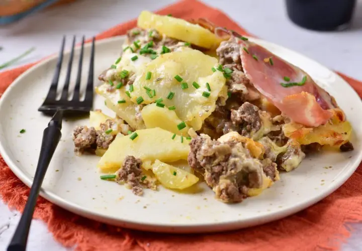 Zapiekanka ziemniaczana z mięsem mielonym, jak u Ani Gotuje, na talerzu, posypana szczypiorkiem. Pyszne danie!