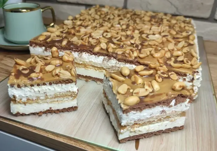 Pyszny snickers bez pieczenia z warstwami kremu, czekolady i orzeszków ziemnych. Idealny deser na każdą okazję.