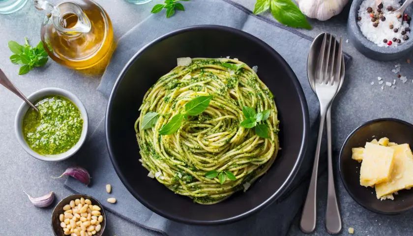 Pyszny obiad bez mięsa: spaghetti z pesto, świeżą bazylią, orzeszkami pinii i parmezanem.