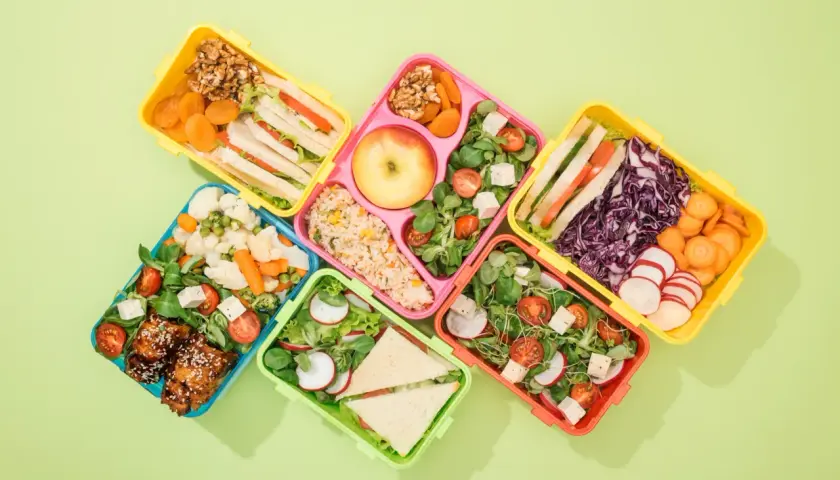 Kolorowe pojemniki z pysznym lunch do pracy: kanapki, sałatki, ryż, owoce i warzywa.
