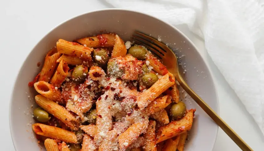 Penne z sosem pomidorowym, oliwkami i startą mozzarellą, posypane płatkami chili. Idealny makaron z mozzarellą na szybki obiad.