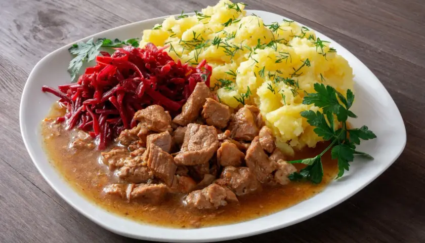 Gulasz z łopatki z ziemniakami i buraczkami, udekorowany natką pietruszki i koperkiem. Pyszny, domowy obiad.