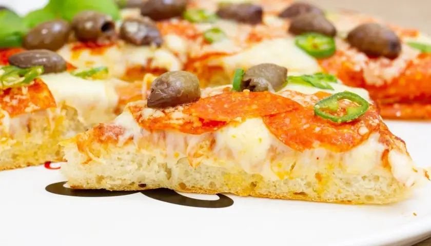 Pyszna pizza z patelni z pikantnym salami, oliwkami i papryczką. Idealna na szybki obiad.