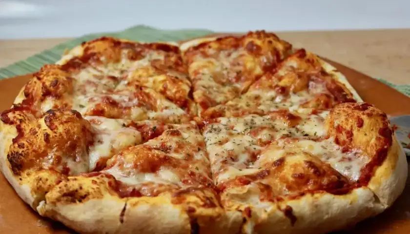 Pyszne, gorące ciasto na pizzę z ciągnącym się serem i aromatycznymi ziołami, pokrojone na kawałki.