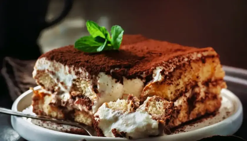 Pyszne tiramisu Ani gotuje, z kremem i biszkoptami, posypane kakao i udekorowane miętą.