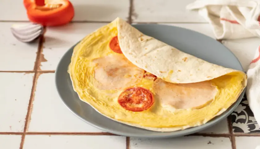 Pyszna, ciepła kolacja: omlet z tortillą, pomidorkami i szynką. Idealny na szybki posiłek.