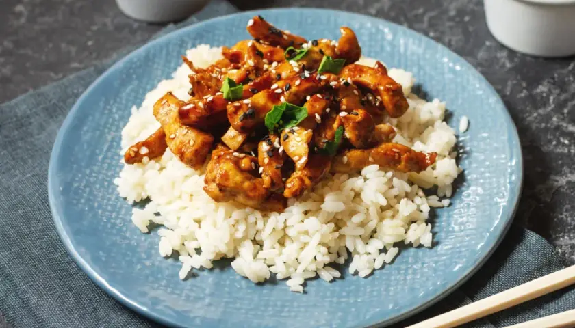 Pyszny kurczak w sosie teriyaki, podany na białym ryżu, posypany sezamem i szczypiorkiem. Idealny posiłek na szybki obiad.
