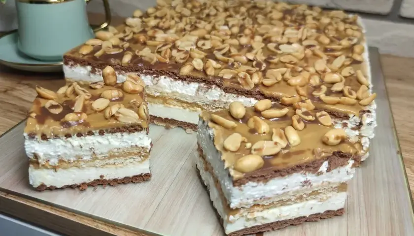 Pyszny snickers bez pieczenia z warstwami kremu, czekolady i orzeszków ziemnych. Idealny deser na każdą okazję.