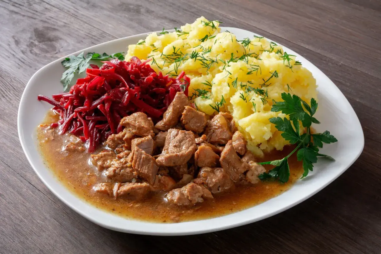 Gulasz z łopatki z ziemniakami i buraczkami, udekorowany natką pietruszki i koperkiem. Pyszny, domowy obiad.