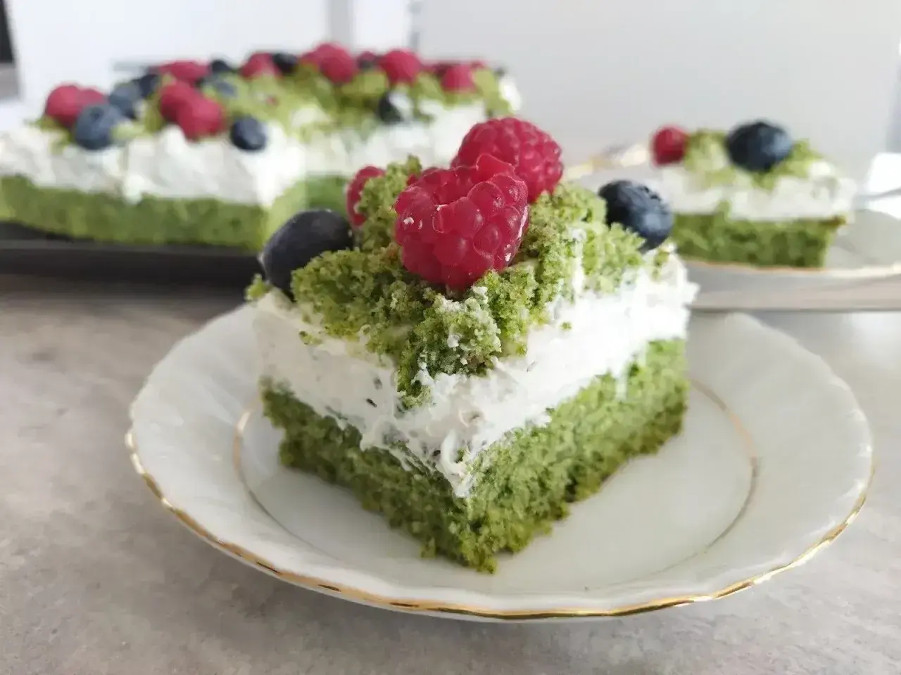 Zielony biszkopt z kremem mascarpone, udekorowany malinami i borówkami. Pyszne ciasto leśny mech z mascarpone.