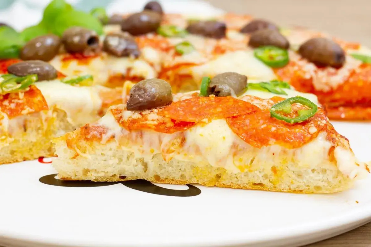 Pyszna pizza z patelni z pikantnym salami, oliwkami i papryczką. Idealna na szybki obiad.