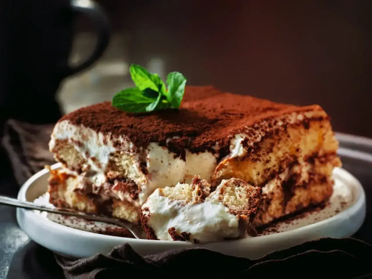 Pyszne tiramisu Ani gotuje, z kremem i biszkoptami, posypane kakao i udekorowane miętą.