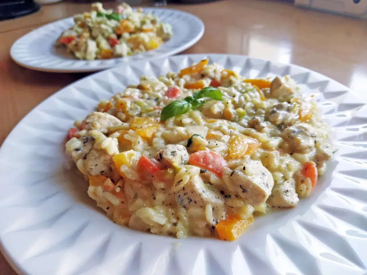Pyszne risotto z kurczakiem, papryką i bazylią, podane na białym talerzu. Idealne na obiad.