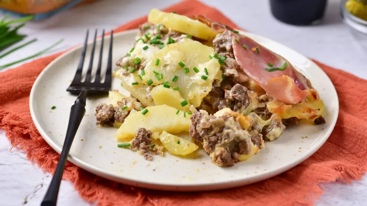 Zapiekanka ziemniaczana z mięsem mielonym, jak u Ani Gotuje, na talerzu, posypana szczypiorkiem. Pyszne danie!
