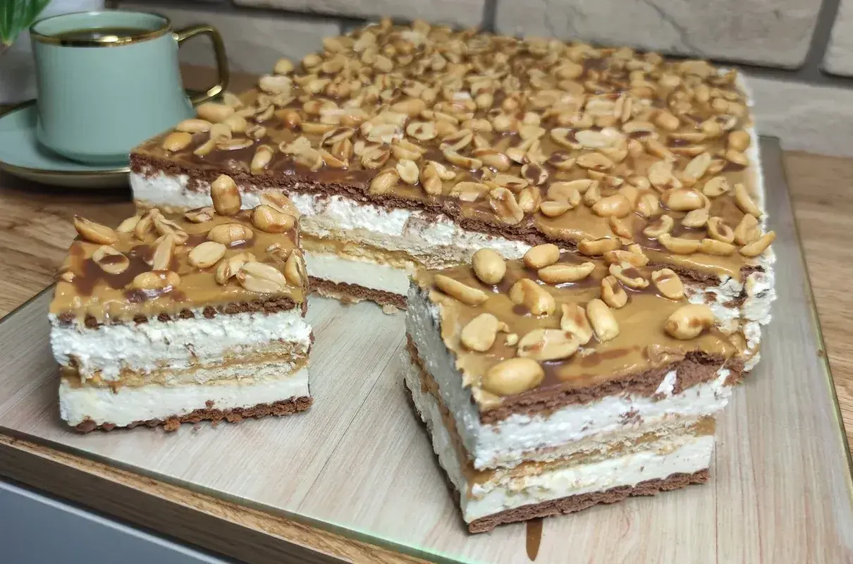 Pyszny snickers bez pieczenia z warstwami kremu, czekolady i orzeszków ziemnych. Idealny deser na każdą okazję.