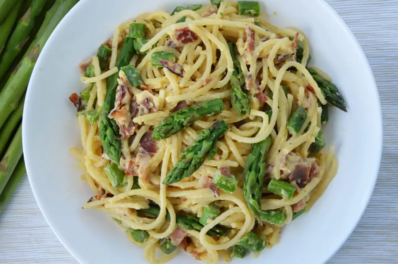 Pyszna carbonara ze szparagami i chrupiącym boczkiem na talerzu.