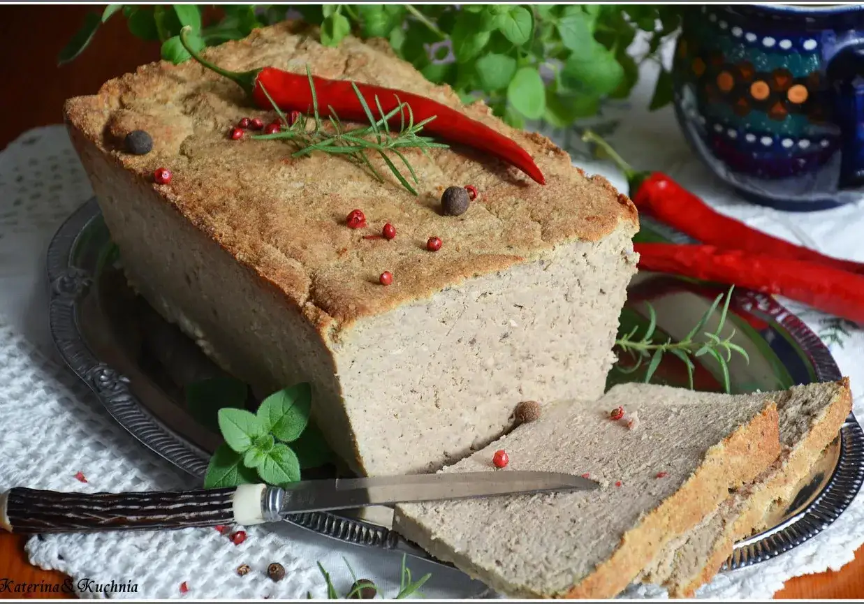 Domowy pasztet mieszany drobiowo-wieprzowy, udekorowany papryczką chili i ziołami, podany z pieczywem.