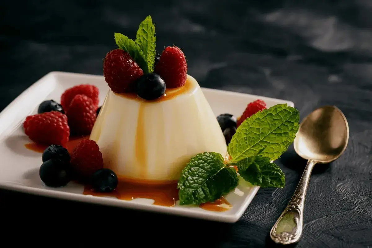 Panna cotta z malinami i borówkami, polana karmelem. Idealny przepis na deser.