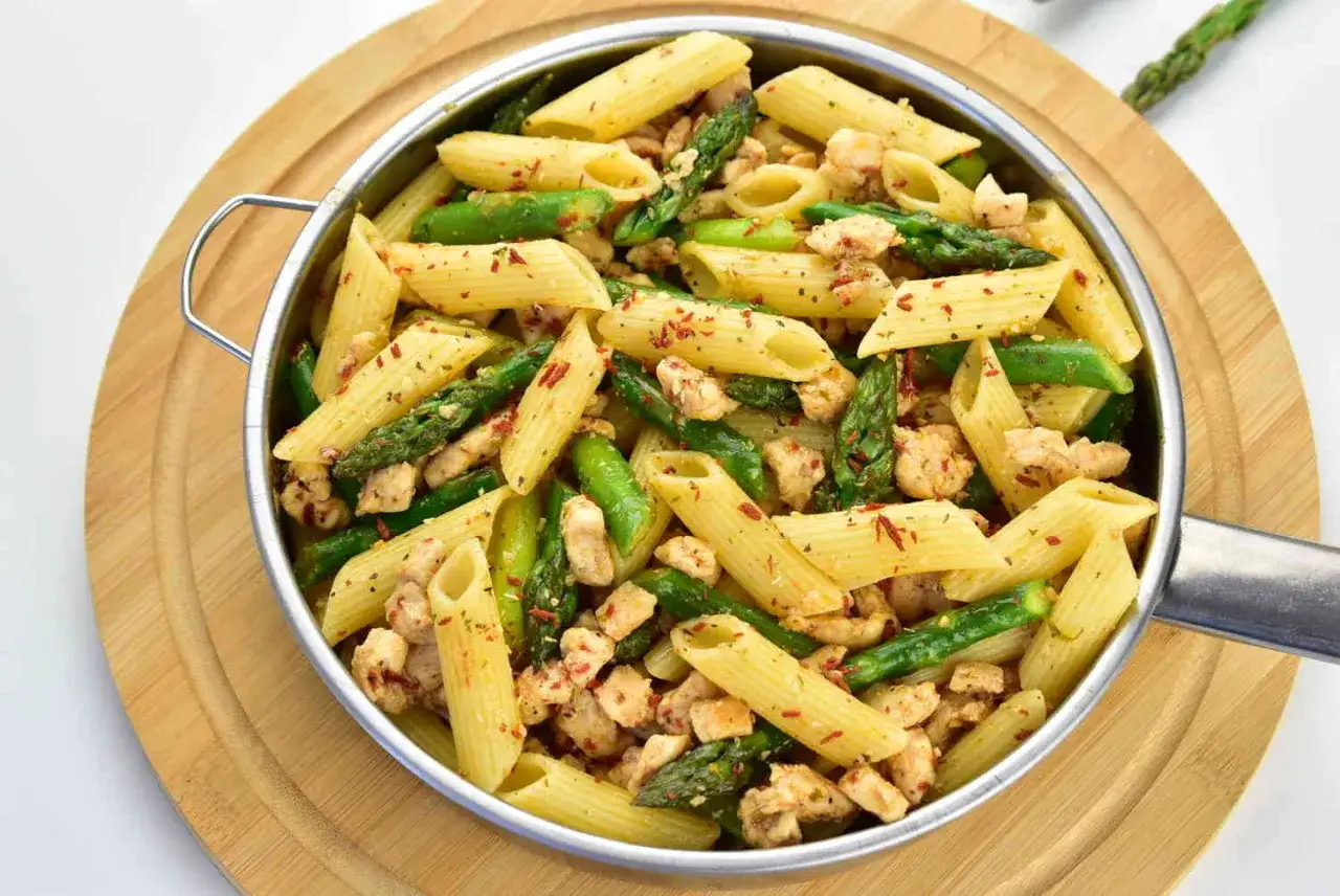 Ania gotuje szybki obiad: makaron penne z kurczakiem i szparagami, posypany papryką.