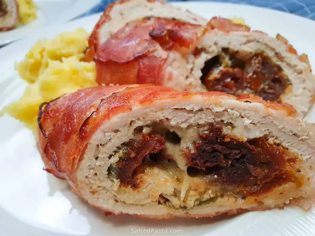 Pyszna rolada z kurczaka owinięta boczkiem, z soczystym nadzieniem z suszonych pomidor&oacute;w i sera, podana z pur&eacute;e ziemniaczanym.