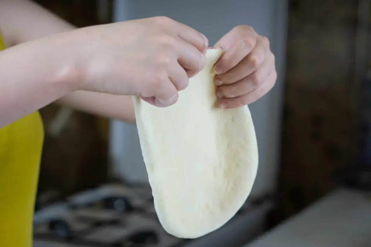 Ręce formują elastyczne ciasto, idealne do szybkiego przepisu na ciasto do pizzy.