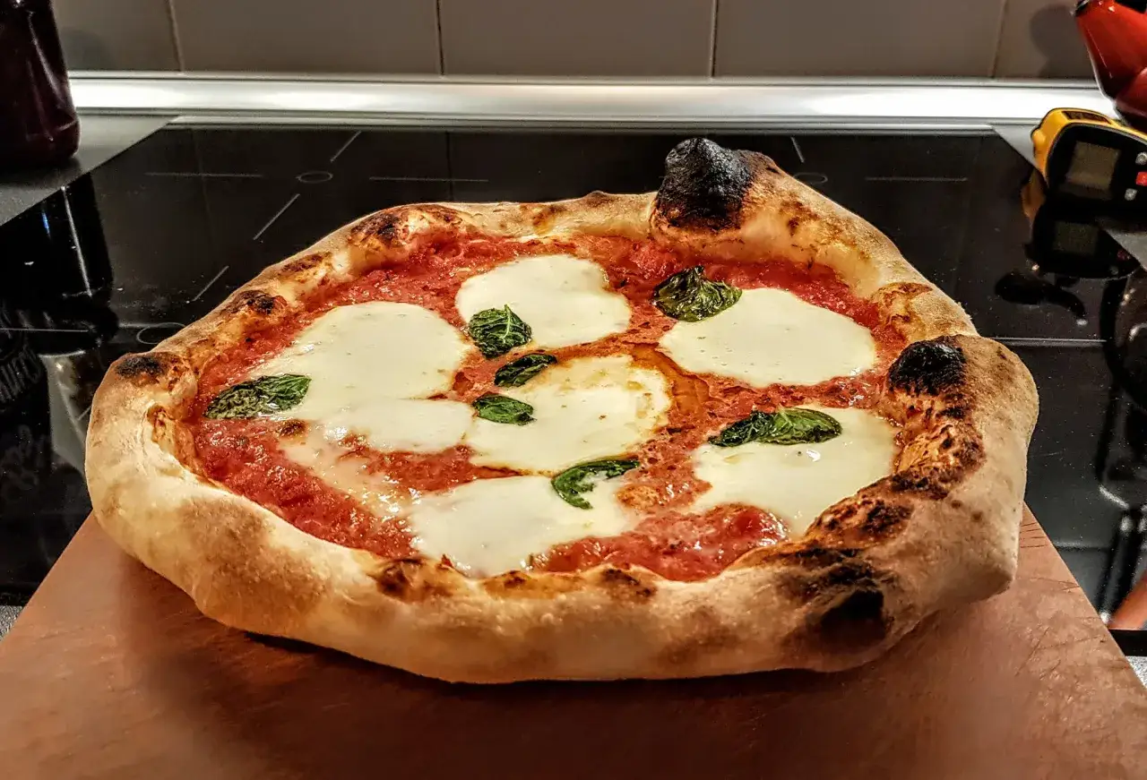 Pyszny, domowy spód do pizzy Margherita z roztopioną mozzarellą i świeżą bazylią, idealnie wypieczony.