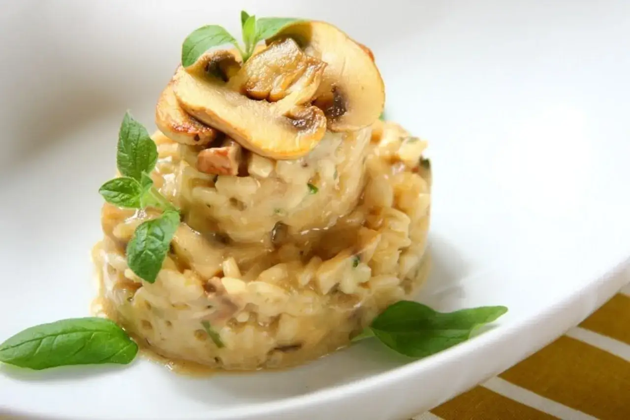 Aromatyczne risotto z kurczakiem i grzybami, udekorowane świeżą bazylią. Kremowe, pyszne danie.
