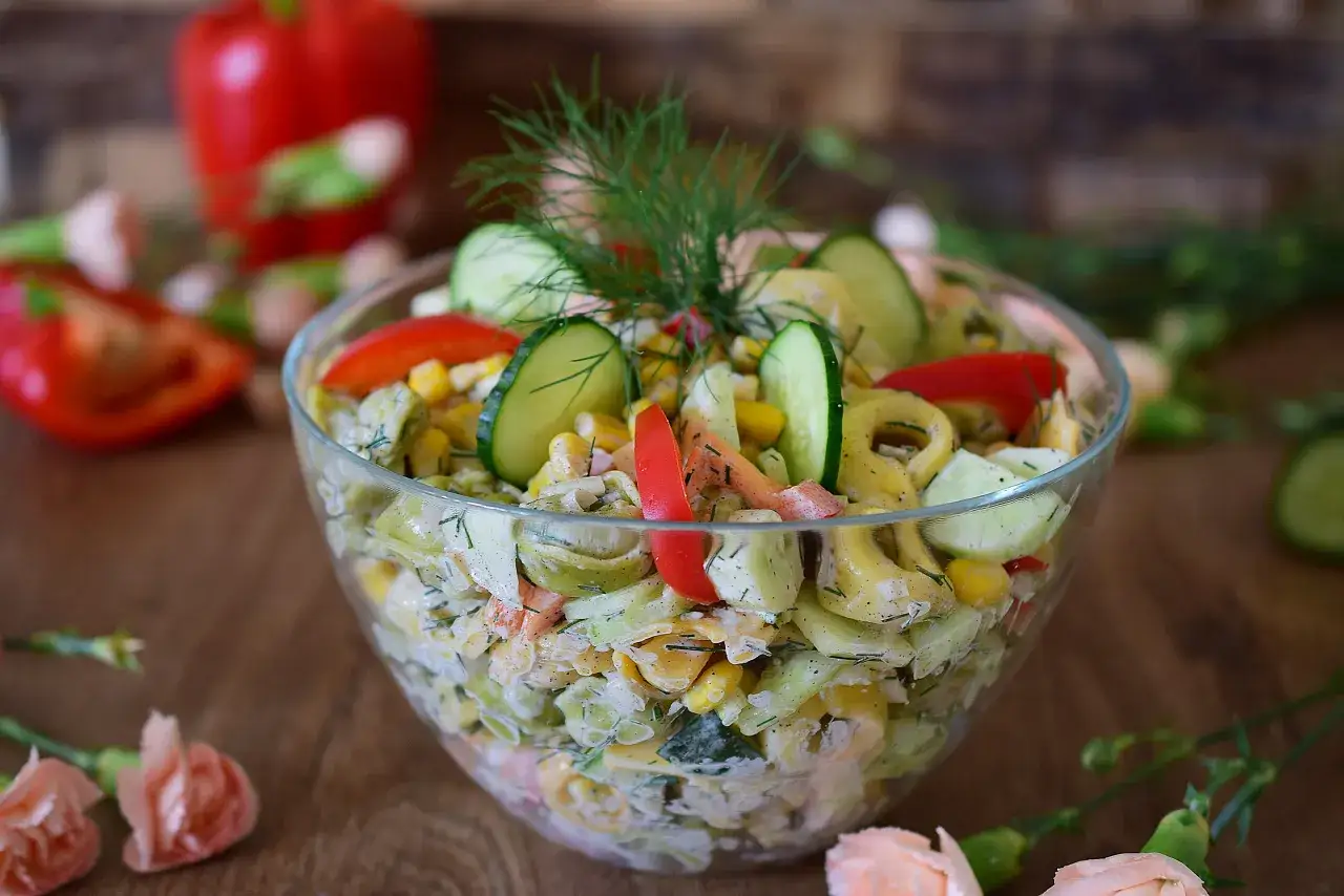 Pyszna sałatka z tortellini, og&oacute;rka, kukurydzy i papryki, udekorowana koperkiem. Idealna na letnie przyjęcie, to najlepsza sałatka z tortellini!