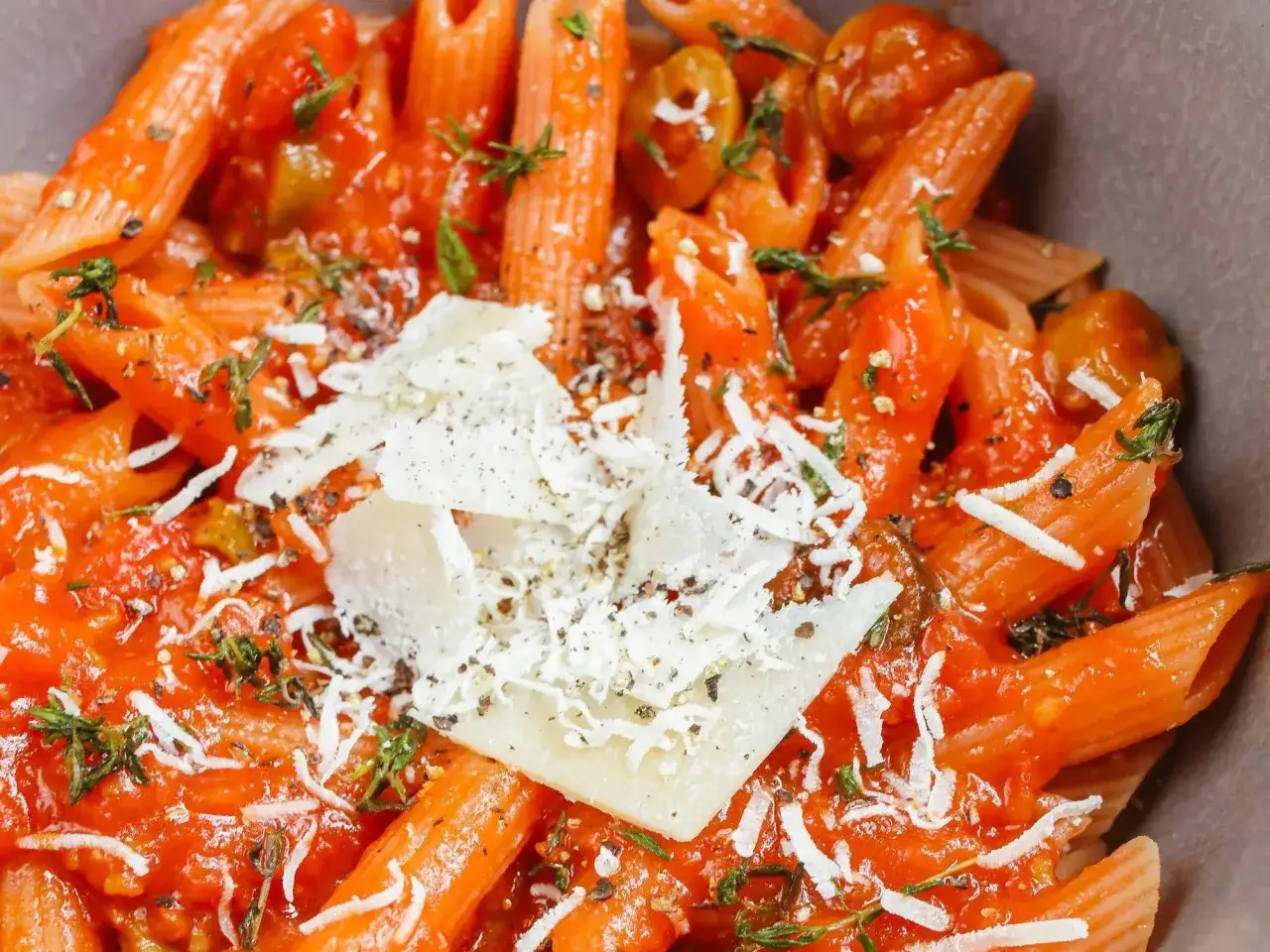 Szybki obiad z makaronem penne w sosie pomidorowym, posypany parmezanem i ziołami.